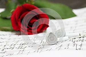 Red rose, earphones, piano sheet music