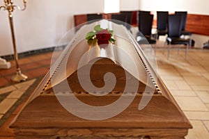 Red rose flower on wooden coffin in church