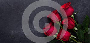 Red rose flowers bouquet on black stone background Valentine`s day greeting card Copy space Horizontal banner