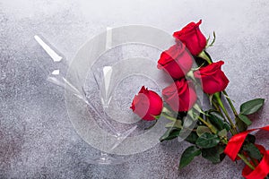 Red rose flowers bouquet, champagne glasses on stone background Valentine`s day greeting card Copy space