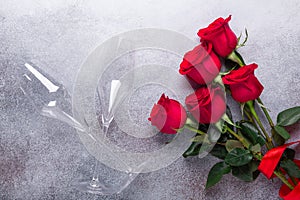 Red rose flowers bouquet, champagne glasses on stone background Valentine`s day greeting card Copy space