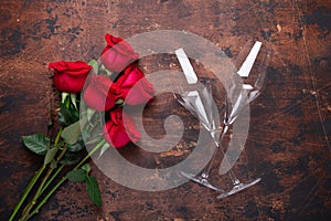 Red rose flowers bouquet and champagne glasses on wooden background Valentine`s day greeting card Copy space Top view