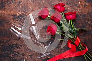 Red rose flowers bouquet and champagne glasses on wooden background Valentine`s day greeting card Copy space Top view