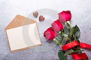Red rose flowers bouquet, chocolate sweets on stone background Valentine`s day greeting card Copy space