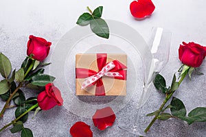 Red rose flowers bouquet, gift box, champagne glasses on stone background Valentine`s day greeting card Top view