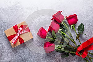 Red rose flowers bouquet, gift box on stone background Valentine`s day greeting card Copy space