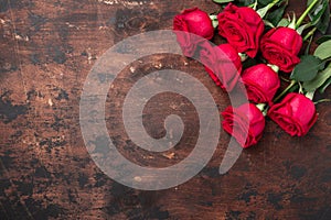 Red rose flowers bouquet on wooden background Valentine`s day greeting card. Copy space. Top view