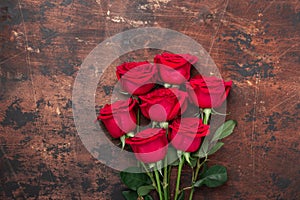 Red rose flowers bouquet on wooden background Valentine`s day greeting card. Copy space. Top view