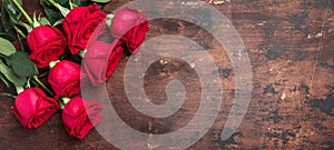 Red rose flowers bouquet on wooden background Valentine`s day horizontal banner. Copy space. Top view