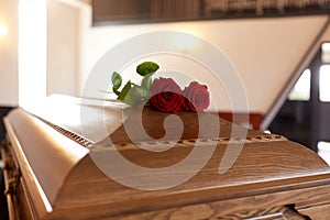 Red rose flowers on wooden coffin in church