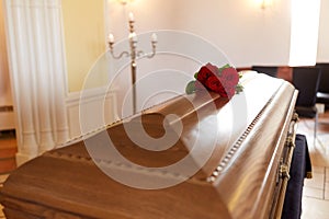 Red rose flowers on wooden coffin in church