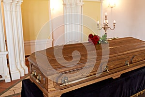 Red rose flowers on wooden coffin in church photo