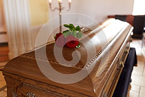 Red rose flowers on wooden coffin in church photo