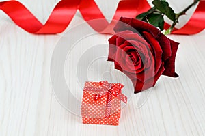 Red rose and gift box on a wooden table
