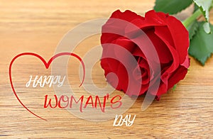Red rose isolated on a wooden background. Text \'Happy woman\'s day\'. photo