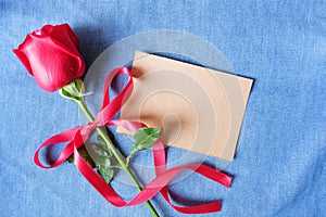 Red rose and paper card on blue jean background for Valentine& x27;s background concept