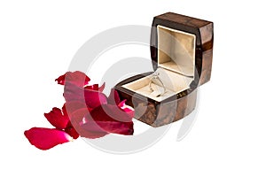 Red rose petals with diamond ring on white