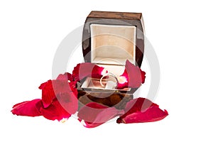 Red rose petals with diamond ring on white