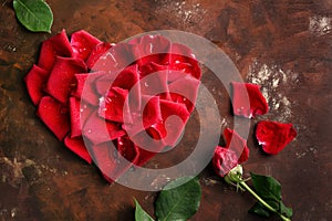 Red rose petals in heart shape on dark brown and golden background. Love, romance, anniversary, valentine`s day concept