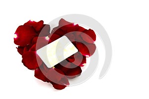 Red rose petals in a heart shape and old card isolated on white