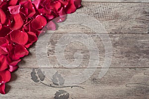 Red rose petals on the wooden background. Rose Petals Border on a wooden table. Top view, copy space. Floral frame.
