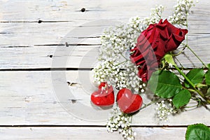 Red rose and two hearts on white painted rustic wooden planks, romantic love greeting card for Valentine`s Day or Motherâ€™s Day,