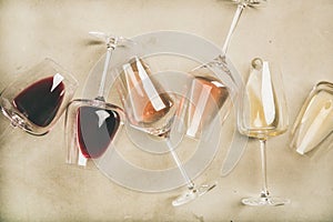 Red, rose and white wine in glasses over grey background