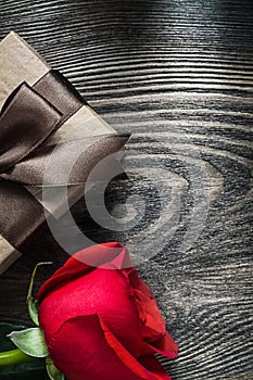 Red rose wrapped present box on wooden board holidays concept