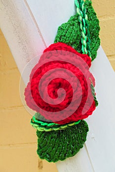 Red rose yarn bomb on white city Victorian bracket on yellow brick city building detail