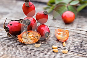 Red rosehips and cut berries in half with seeds on a wooden table