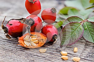 Red rosehips and cut berries in half with seeds on a wooden table