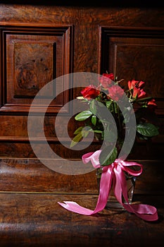 Red roses bouqet on the vintage old wooden piano photo