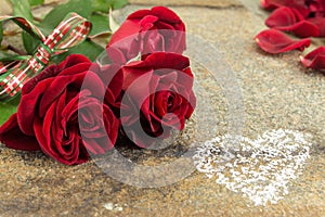 Red roses bouquet with ribbon on stone table