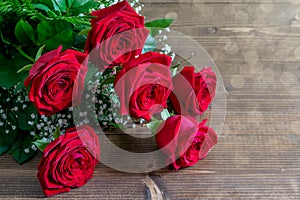 Red roses bouquet on the wooden table in sunlights. Nice gift for Valentine`s day or Mother`s day