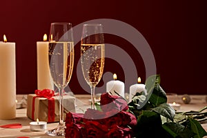 Red roses with gift and glasses of champagne on table. Valentines Day celebration