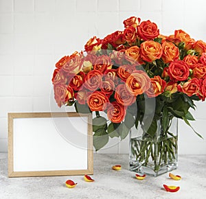 Red roses in a glass vase with an empty photo frame