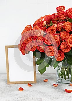 Red roses in a glass vase with an empty photo frame