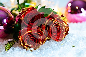 Red roses with glitte in snow and christmas balls