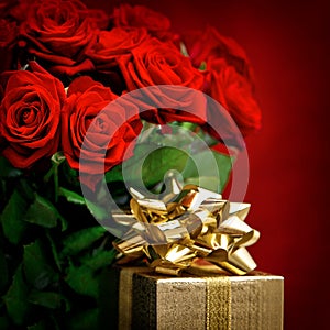 Red roses and golden gift box. Festive decoration