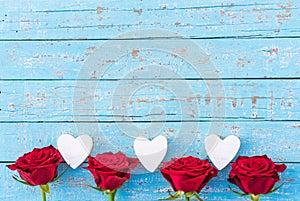 Red roses and hearts border on light blue wood background for Wedding or Valentine`s Day