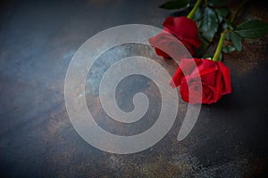 Red roses lie on a textured spotted marble background. A sign of condolence, sympathy for the loss. Space for your text photo