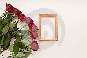 Red roses on a light background and a frame for a photo