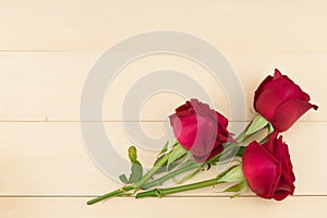 Red roses on light brown wood background
