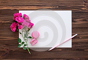 Red roses, pencil and blank  paper card on wooden background. Copy space, flat lay