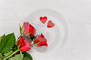 Red roses and two wooden hearts on textured concrete background from above. Love and togetherness concept. Valentines day, mothers