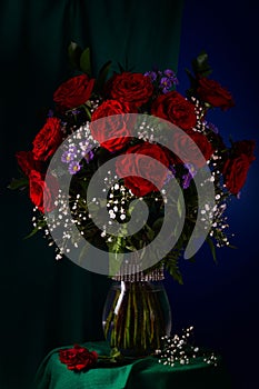 Red roses, white gypsophila and lilac asters in a glass vase.