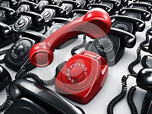 Red rotary phone surrounded by black phones