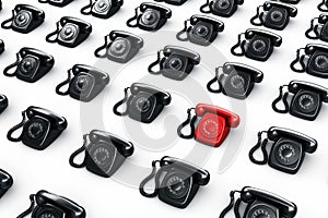 Red rotary phone surrounded by black phones