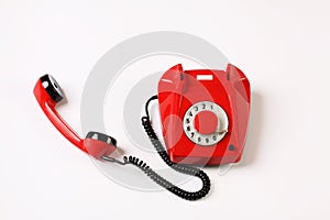 Red rotary telephone off hook on white background