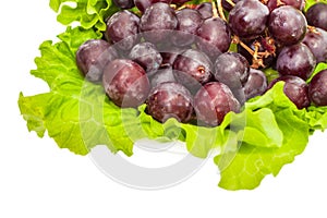 Red round grapes with salad fresh green leaves on light ceramic plate isolated white background